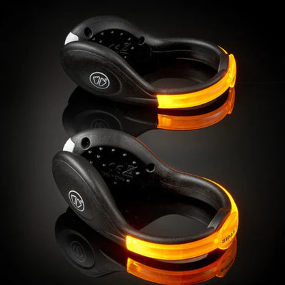 Two black and orange LED clip lights on a reflective surface with a dark background