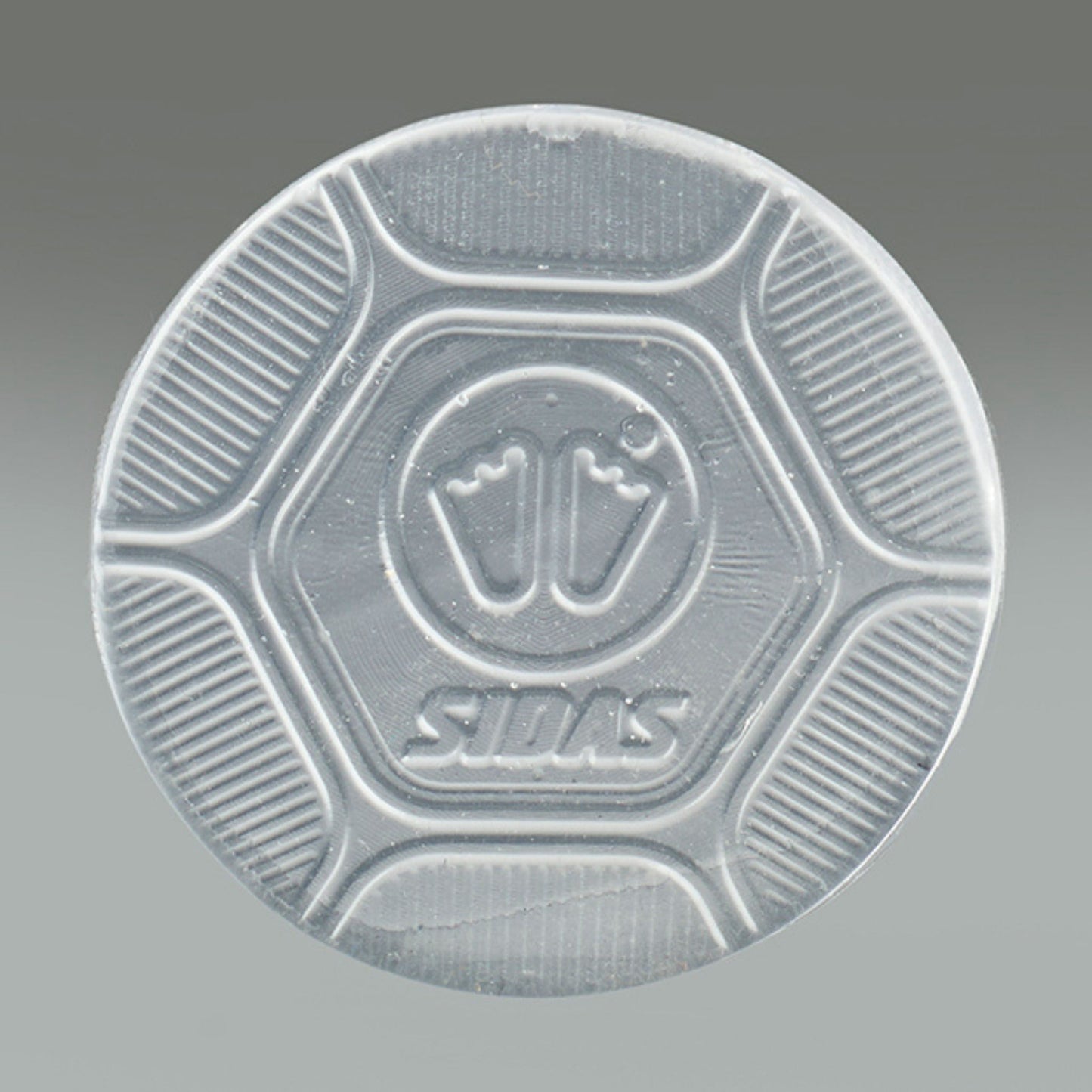 Clear plastic disc with embossed design and 'Sidas' branding on a gray background