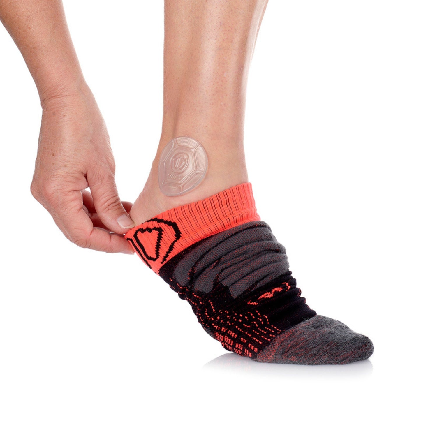 Person wearing a black and red sock with a clear adhesive patch on a white background